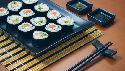 Sushi maki rolls presented on a tray with sauces and chopsticks