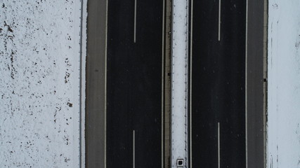 aerial top view of highway with low traffic on snowy winter day