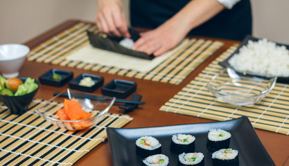 Chef hands preparing sushi with plate of finished maki rolls © David Pereiras