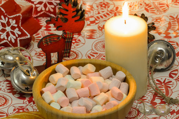 Marshmallow in a wooden plate. Lighted candle on the table. New Year's composition
