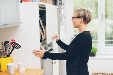 Woman opening a cabinet above her oven