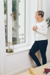 Woman standing looking out of a window at home