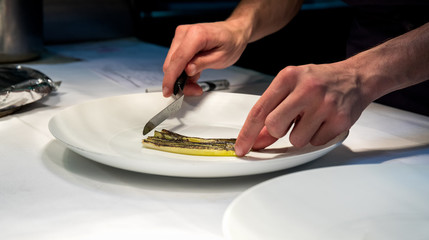 Chef preparing a slice of grilled zucchini on a white plate