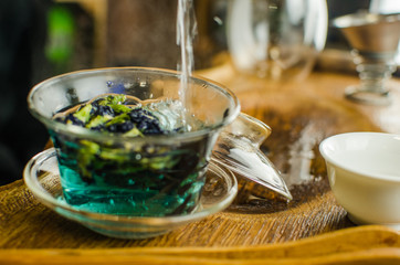 Organic blue tea Anchan in a teapot and a cups on wooden background