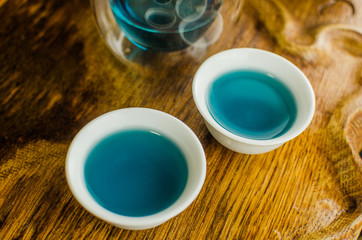 Organic blue tea Anchan in a teapot and a cups on wooden background