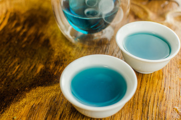 Organic blue tea Anchan in a teapot and a cups on wooden background
