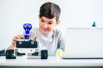 Waist up of a smiling boy testing modern robot