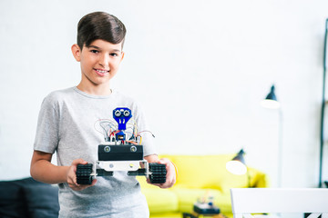 Pleasant little boy holding his robot at home