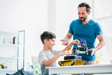Positive man being involved in robotic technologies with his son