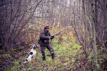 male hunter, in the forest, with arms, dog Springer Spaniel, hunting, autumn