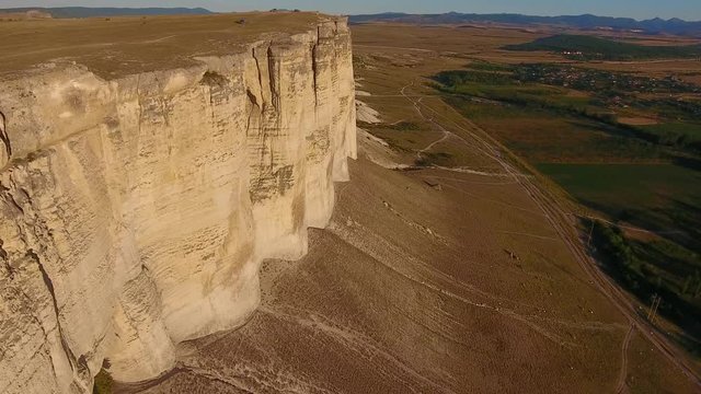 Aerial view shadow flying rocks to White Canyon, car goes, bright sun at sunset, cliffed Tropical 4K. Aerial video of cliffed coast line Crimea Rocks line.