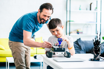 Caring smiling father helping his son with engineering