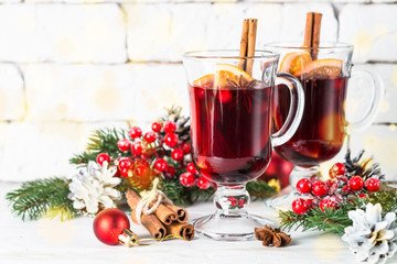 Mulled wine in glass mug with fruit and spices on white.