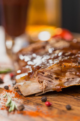 Delicious barbecued ribs seasoned with a spicy basting sauce and served with chopped fresh vegetables on an old rustic wooden chopping board in a country kitchen