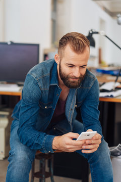 Bearded man texting a message on a smartphone