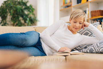 Obraz premium Attractive mature woman relaxing with a good book