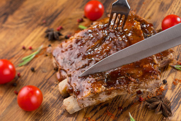 Delicious barbecued ribs seasoned with a spicy basting sauce on an old rustic wooden shopping board...