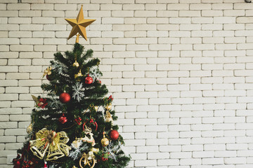 Close up of decorated Christmas tree with white brick wall.