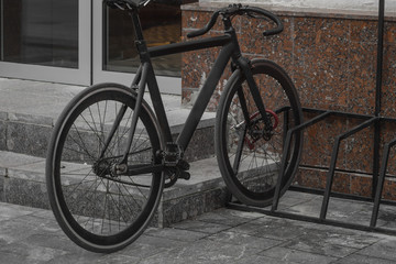 Black sports bike on the fence on a pedestrian street. Autumn day