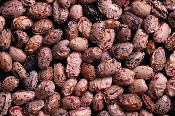 Soaked light speckled kidney beans on black background