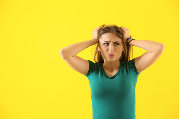 Emotional young woman after making mistake on color background