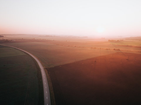 Foggy sunrise over road surrounded by agriculture fields. Early autumn in Joniskis, Lithuania.
