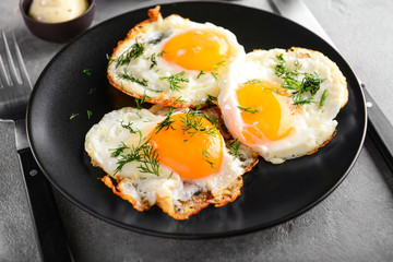 Plate with tasty fried eggs on grey table