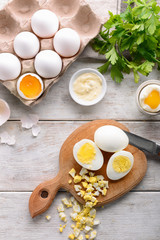 Whole and cut boiled eggs with sauce on wooden table