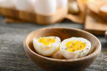 Bowl with tasty boiled eggs on wooden table