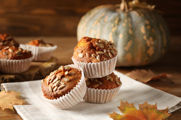 Tasty pumpkin muffins with sunflower seeds on wooden table