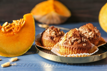 Delicious muffins with sunflower seeds and cut pumpkin on color table