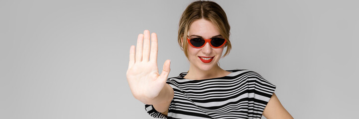 Young girl with glasses shows a hand sign stop.