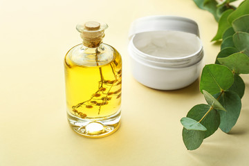Cream and bottle of eucalyptus essential oil on color background