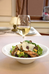 Salad on a plate on a table in a restaurant and a glass of wine