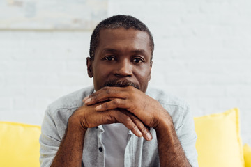 close up of thoughtful african american mature man sitting on sofa