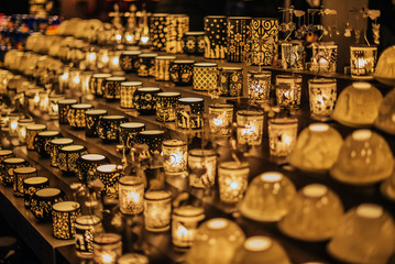 Vienna, Austria - December 24, 2017. Lighting glass candle holders with ornaments in kiosk at Viennese Christmas market. Close view of Xmas fair stall selling craft souvenirs and gifts.