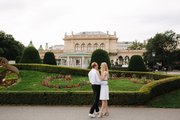 Man and woman dandce in the park by big palace. Love Story of charming couple. Beautiful green background