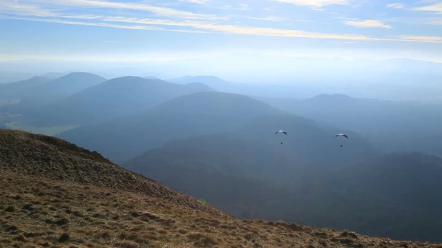 Unidentified people paragliding over a beautiful volcanic landscape in Central Massif in France.