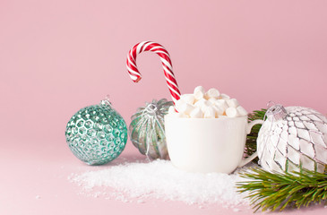 White mug with marshmallows Candy Cane Vintage Christmas New Year balls in the snow on pink background Flat Lay copy space. Winter traditional drink food. Festive decor celebration holiday Baubles