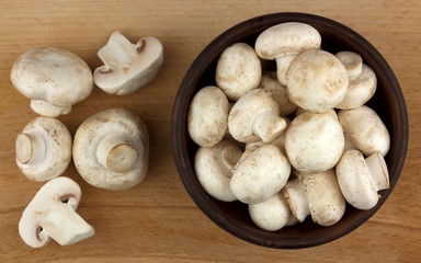 Champignon mushrooms in bowl  on wooden background.