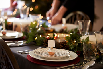 Christmas table setting with bauble name card holder arranged on a plate and green and red table...