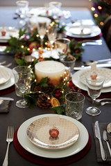 Christmas table setting with bauble name card holder arranged on a plate and green and red decorations, elevated view
