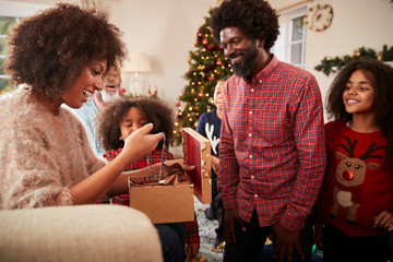 Couple Exchanging Gifts As Multi Generation Family Celebrate Christmas At Home Together
