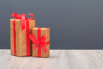 Gift boxes with red ribbons on wooden boards and gray background