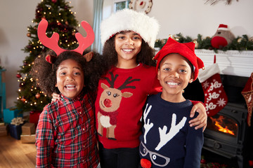 Portrait Of Children Wearing Festive Jumpers And Hats Celebrating Christmas At Home Together