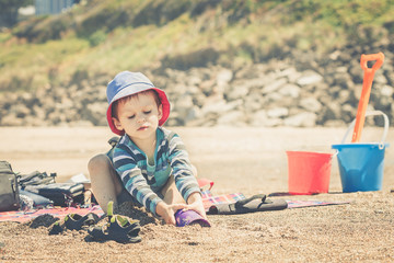 Little boy with cute hat playing with sand