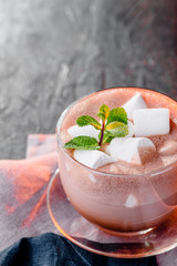 Hot chocolate with marshmallows in a glass cup with mint. Cocoa. sunset orange light
