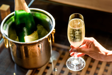Girl hand with manicure hold champagne glasses on a beautiful summer terrace. sparkling champagne glasses