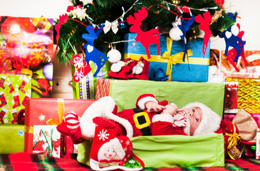 Cute little baby with gift box and garland on knitted fabric