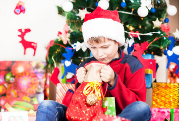 Fototapeta na wymiar beautiful bright cheerful happy child boy upset by a gift for Christmas and New year emotionally surprised and looking inside
